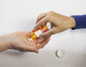 Closeup of woman's hand putting pills in another woman's hand.