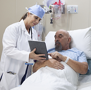 Healthcare provider talking to man in pre-op hospital room.